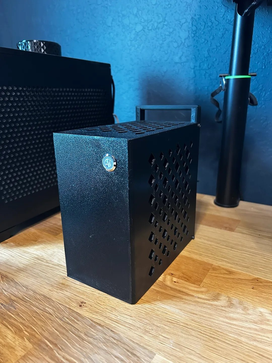 Black 3D printed 3.73L Mini ITX PC case with a printed carry handle, diamond side vents and a lit blue power button