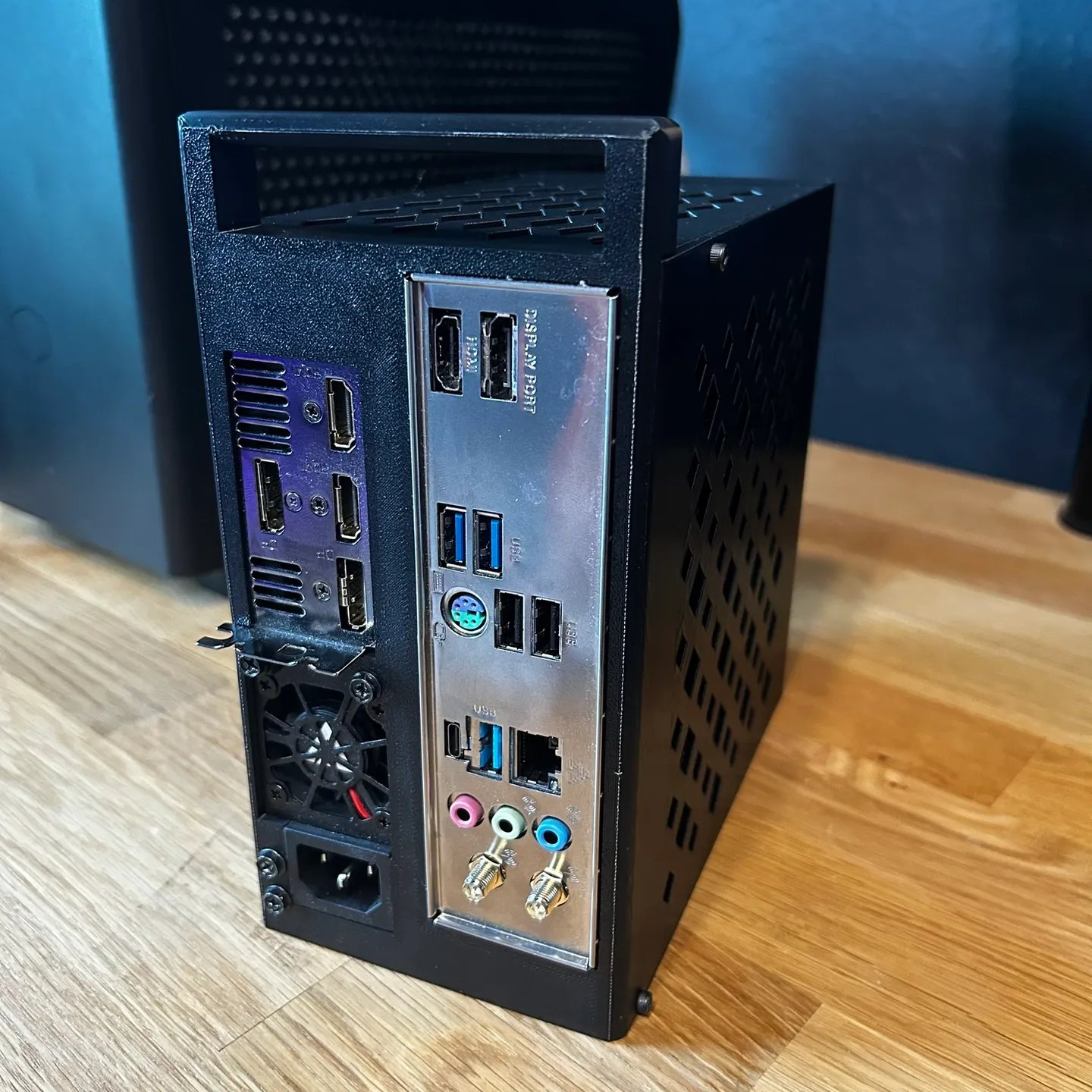 Rear panel of the case showing the motherboard I/O, graphics card display outputs, Flex ATX power supply fan and mains inlet
