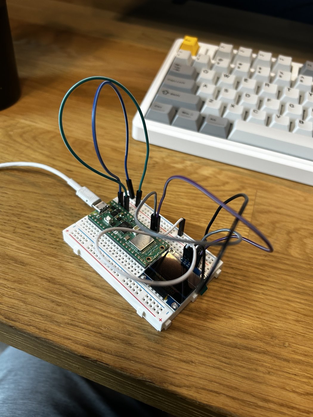 Breadboard with a Raspberry Pi Pico 2 W, a small OLED display and jumper wires running to an I2S microphone